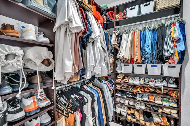 a view of walk in closet with clothes and shoes