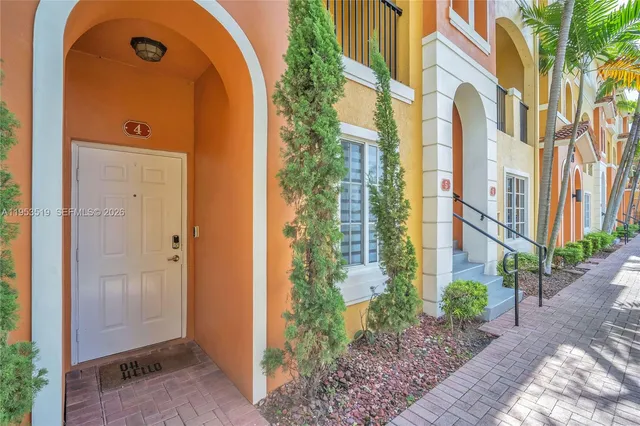 a view of a brick house with plants and wooden fence