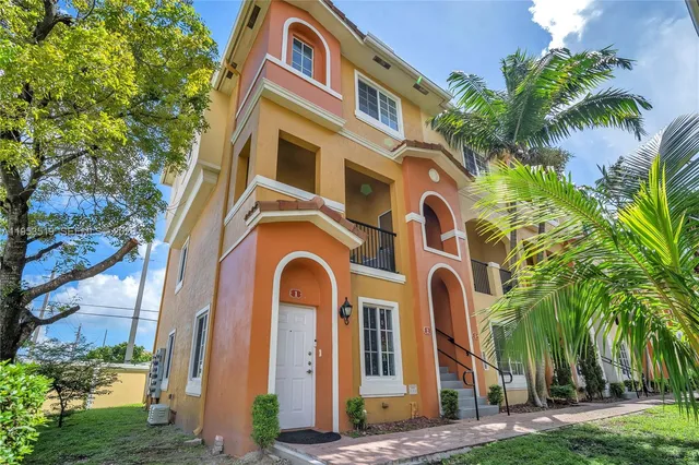 a front view of a multi story residential apartment building with yard and entryway