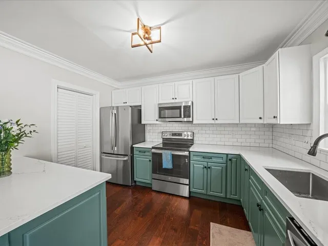 a kitchen with stainless steel appliances white cabinets and wooden floors
