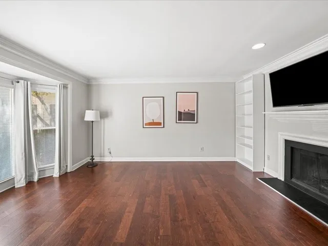 an empty room with windows fireplace and wooden floor