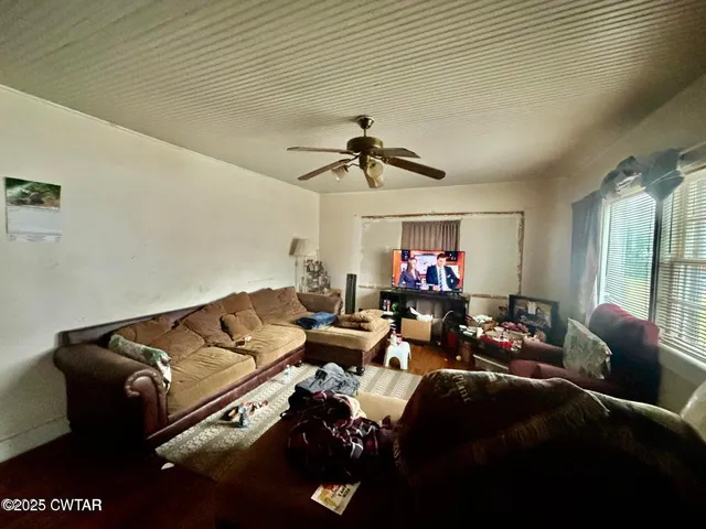 a living room with furniture chess table and a ceiling fan