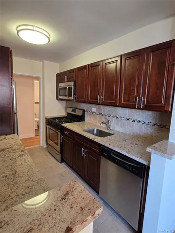 a kitchen with stainless steel appliances granite countertop a stove a sink and a microwave