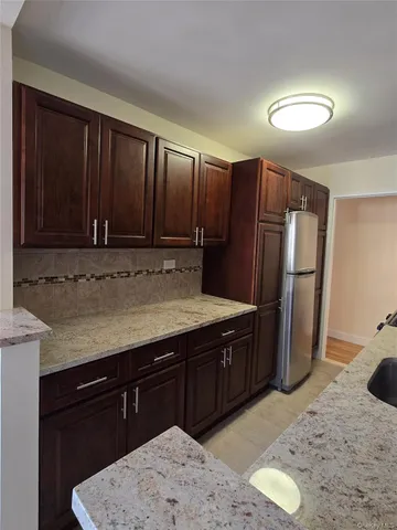 a kitchen with stainless steel appliances granite countertop wooden cabinets a refrigerator and a sink