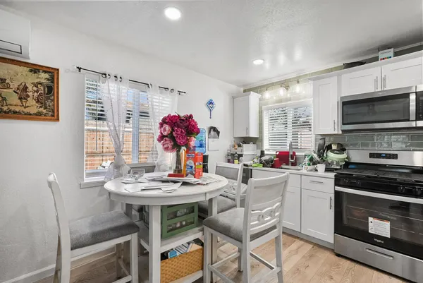 a kitchen with stainless steel appliances a stove a sink dishwasher a dining table and chairs with wooden floor