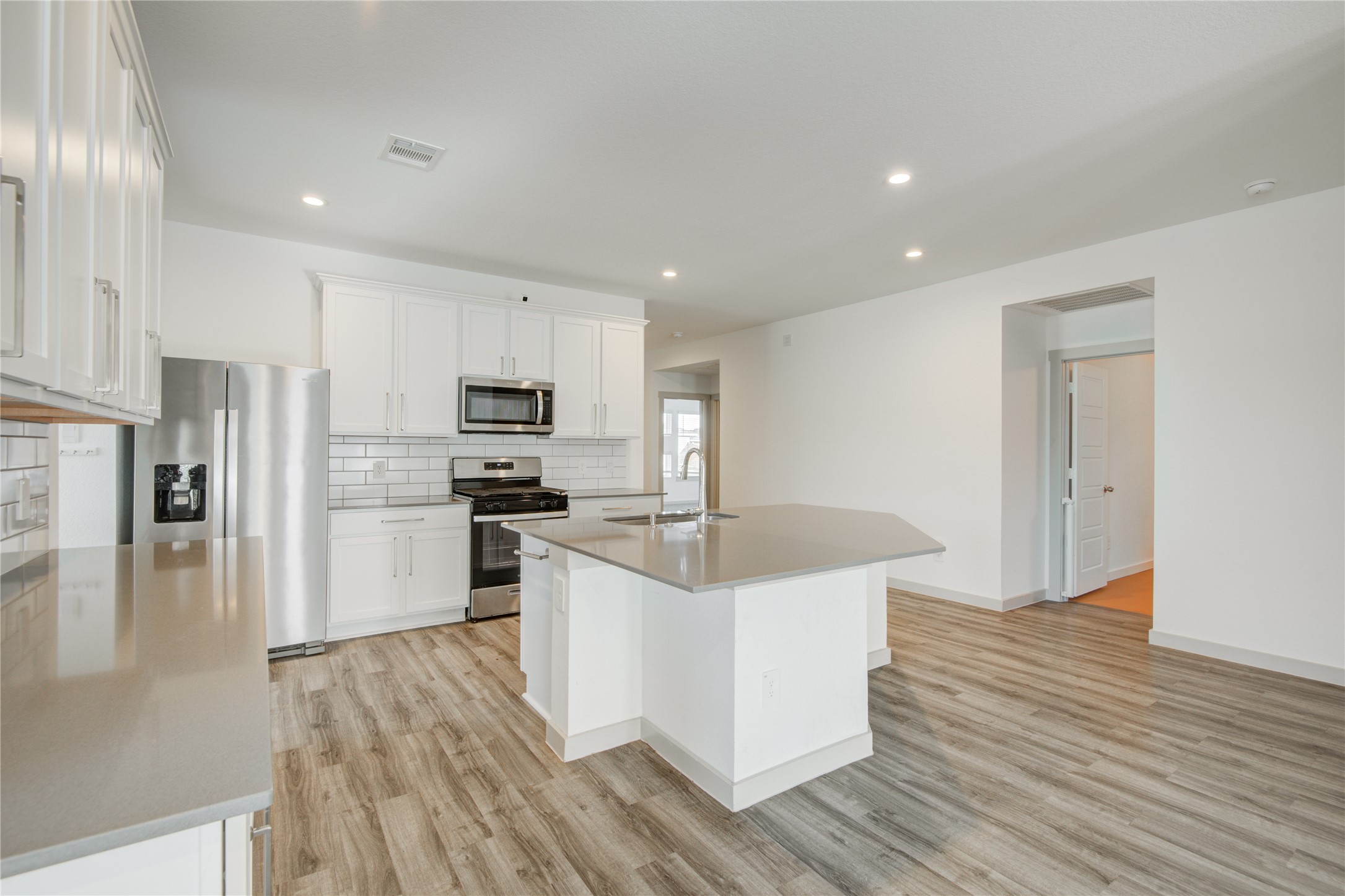 7802 Murciana Drive Rosharon, TX 77583 - Photo 18 of 35 a kitchen with stainless steel appliances kitchen island wooden floors and white cabinets