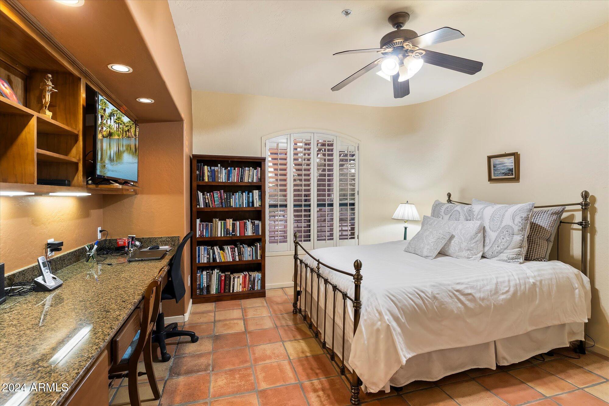 25255 North Ranch Gate Road Scottsdale, AZ 85255 - Photo 38 of 68 a bedroom with a bed a bookshelf and a chandelier