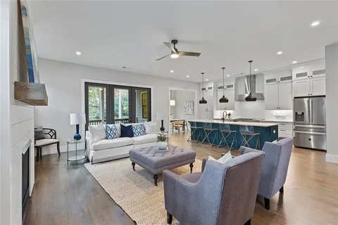 a living room with couches and kitchen view with wooden floor