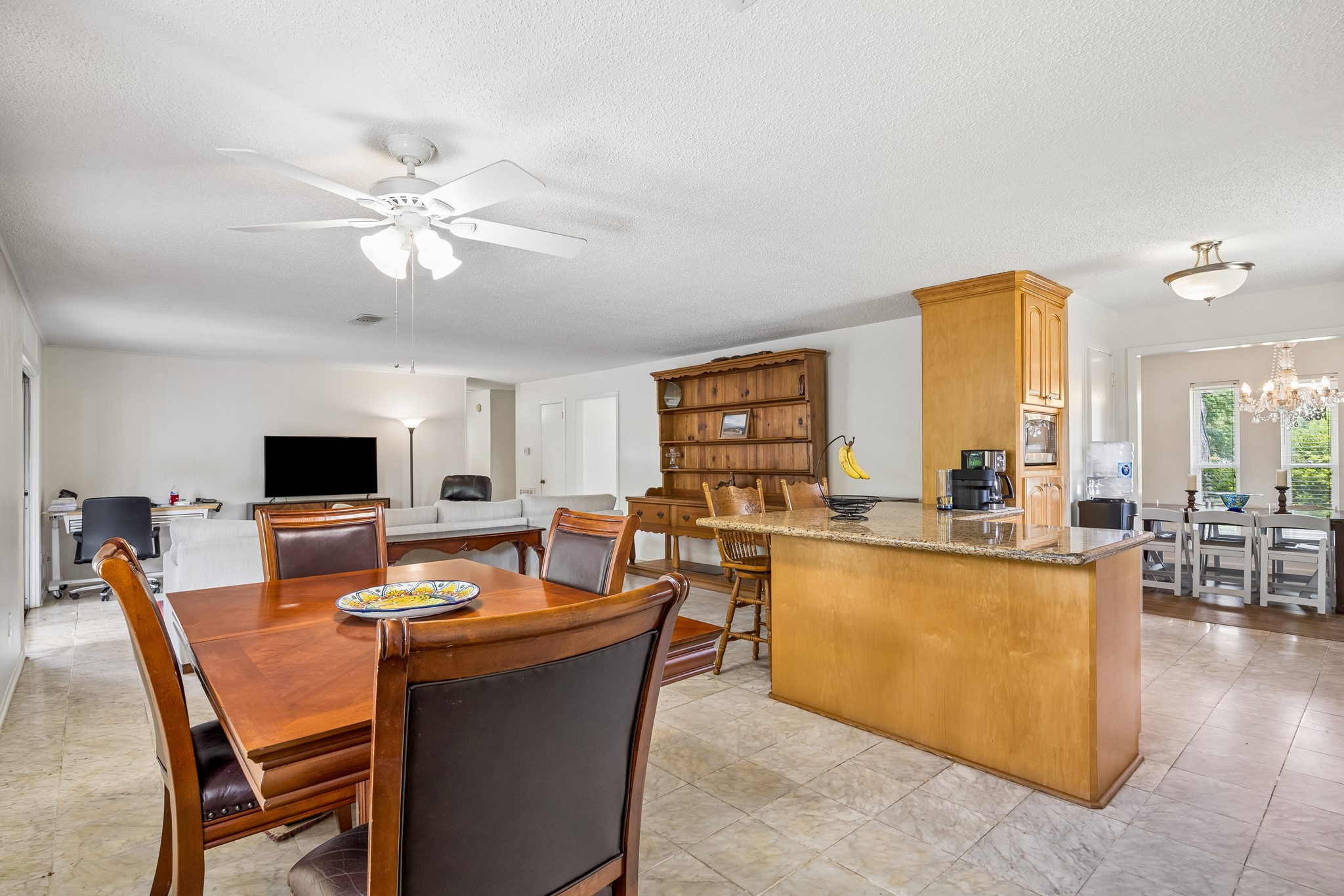 413 Mebane Lane Rosenberg, TX 77471 - Photo 18 of 30 This open-concept living space features a spacious kitchen with a large island and granite countertops, adjacent to a cozy dining area. The room is bright and welcoming, with a ceiling fan and ample natural light. Ideal for entertaining or family gatherings.