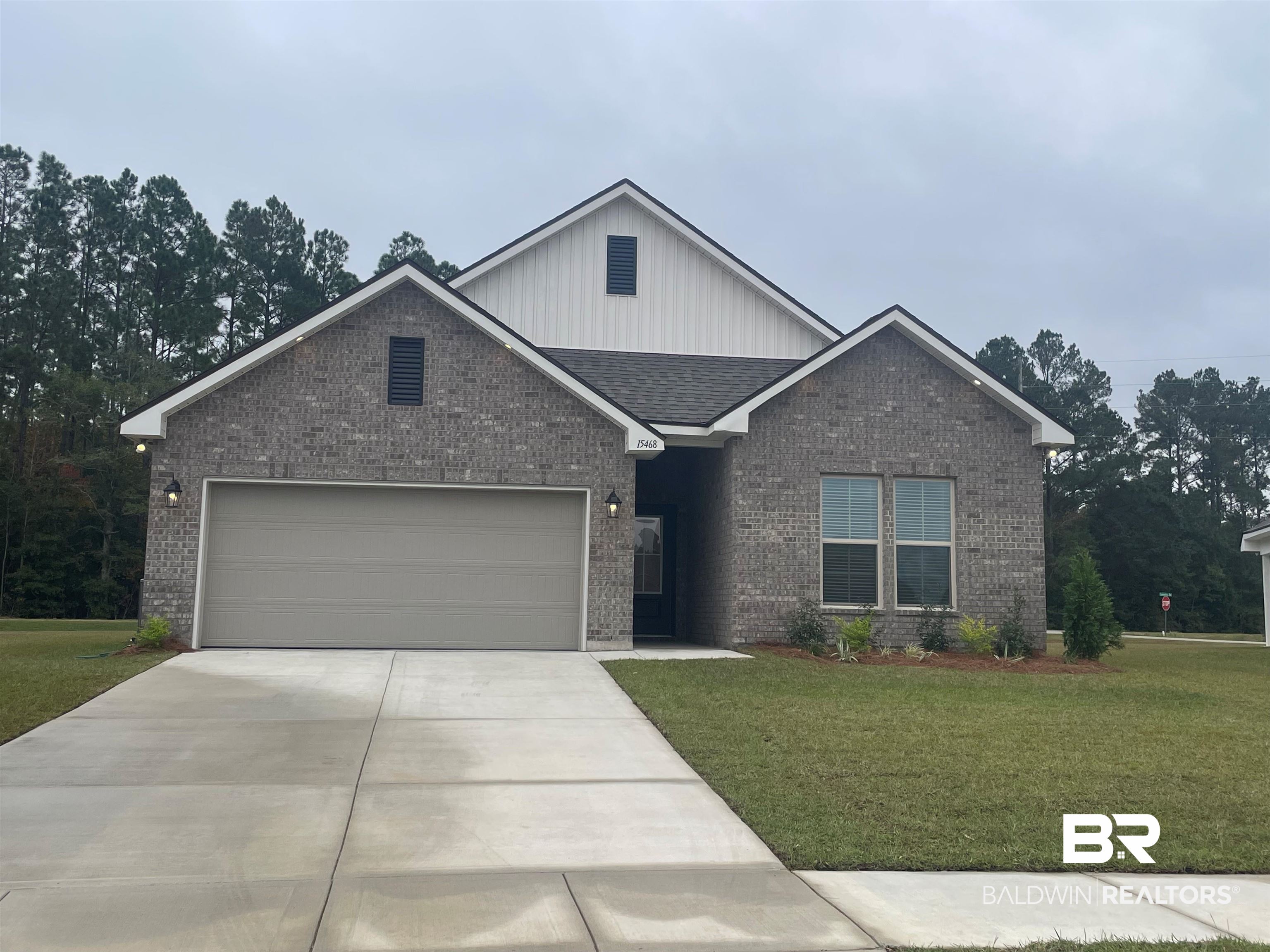 15468 Yellowstone Drive Silverhill, AL 36576 - Photo 1 of 3 View of front of house with a front yard, brick siding, board and batten siding, an attached garage, and driveway