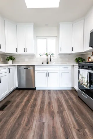 a kitchen with white cabinets and a window