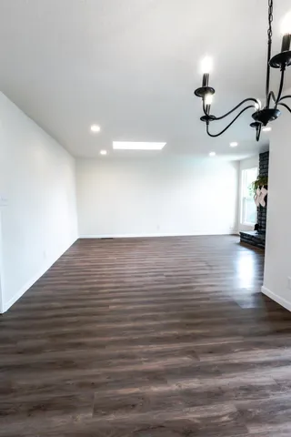 an empty room with wooden floor fireplace and window