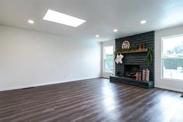 an empty room with wooden floor fireplace and windows