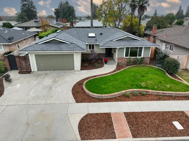 a aerial view of a house with a yard potted plants and a bench