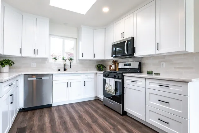 a kitchen with stainless steel appliances granite countertop a sink a stove and cabinets