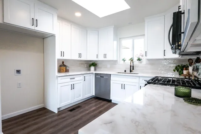 a kitchen with granite countertop white cabinets and white appliances