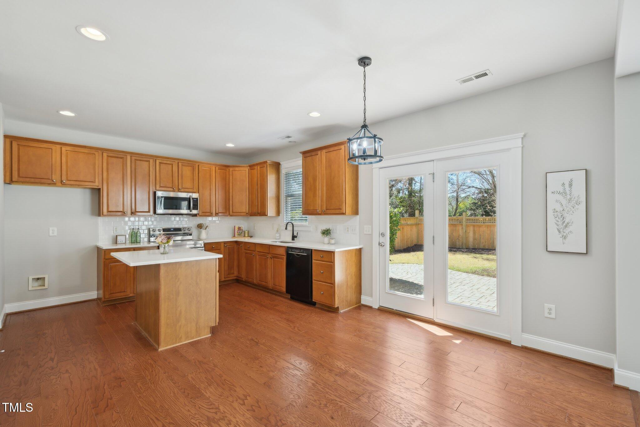 304 Frontgate Drive Cary, NC 27519 - Photo 16 of 41 a large kitchen with stainless steel appliances granite countertop a refrigerator a sink dishwasher a stove and a dining table with wooden floor