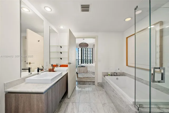 a bathroom with a tub a sink and a large mirror