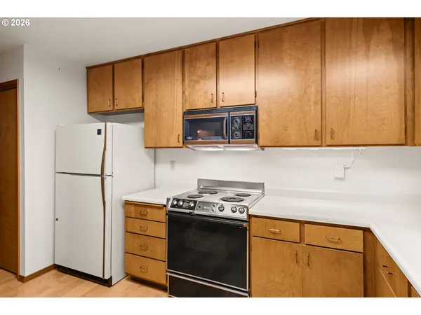 a kitchen with stainless steel appliances granite countertop wooden cabinets a stove a microwave and a refrigerator