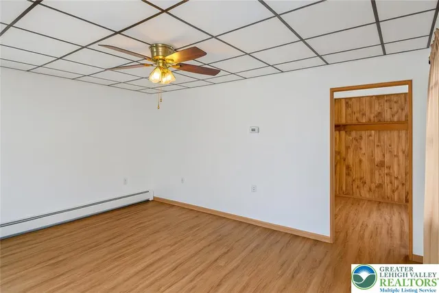 a view of an empty room with a window and wooden floor