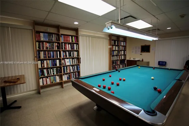 a room with pool table and a bookshelf