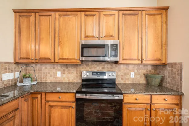 a kitchen with granite countertop a stove a sink and a microwave
