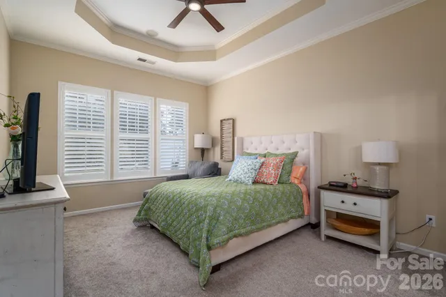 a bedroom with a bed a couch and a flat tv screen on the dresser