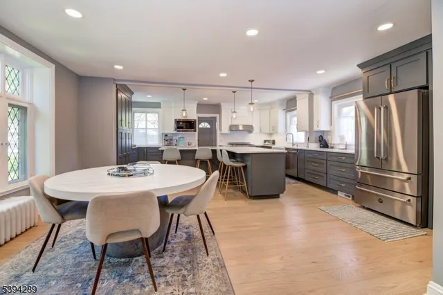 a kitchen with stainless steel appliances kitchen island granite countertop a sink a stove a refrigerator with a dining table and chairs