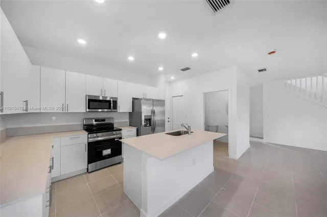 a large kitchen with stainless steel appliances lots of counter space and wooden floor