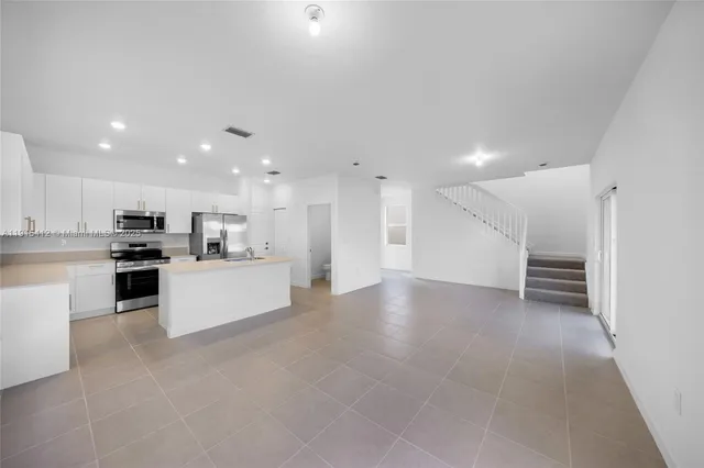 a view of kitchen with kitchen island a sink white cabinets and stainless steel appliances