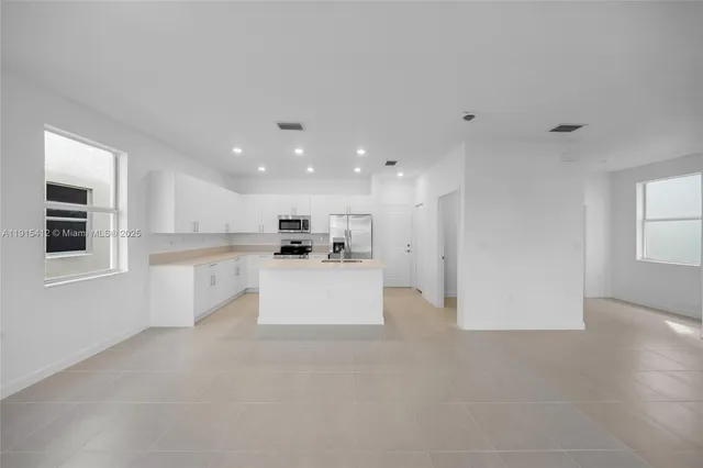 a view of kitchen with kitchen island white cabinets and refrigerator