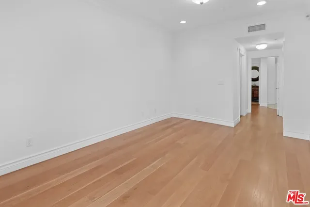 a view of a hallway with wooden floor and a bathroom