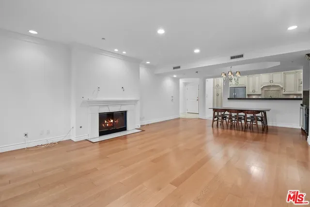 a view of an empty room with wooden floor fireplace and a window
