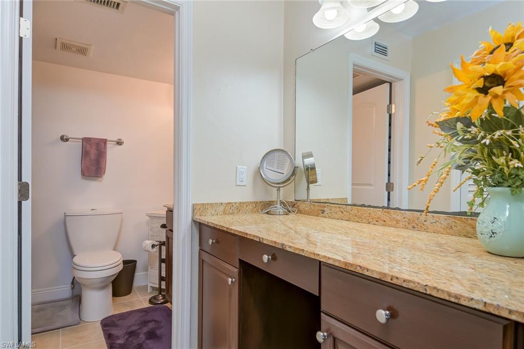 145 Cypress Way East, Unit A Naples, FL 34110 - Photo 12 of 24 a spacious bathroom with a granite countertop sink a toilet and mirror