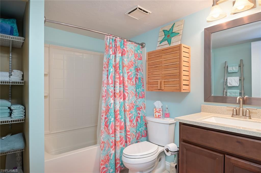 145 Cypress Way East, Unit A Naples, FL 34110 - Photo 18 of 24 a bathroom with a sink a toilet a shower curtain and a bath tub