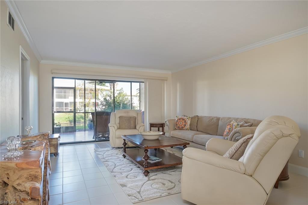 145 Cypress Way East, Unit A Naples, FL 34110 - Photo 3 of 24 a living room with furniture and large windows