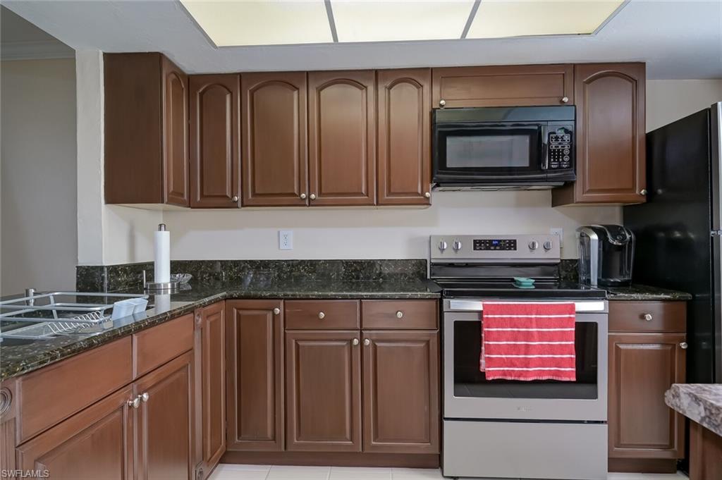 145 Cypress Way East, Unit A Naples, FL 34110 - Photo 8 of 24 a kitchen with granite countertop a stove top oven microwave and cabinets
