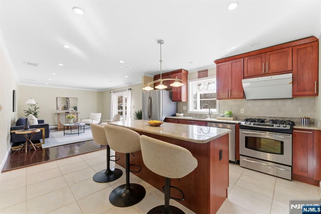 3 Rutgers Court Roseland, NJ 07068 - Photo 7 of 29 a kitchen with stainless steel appliances granite countertop a stove a sink a dining table and chairs with wooden floor