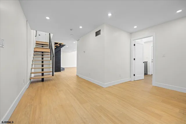 a large white kitchen with kitchen island a large counter top a sink a stove and a wooden floors