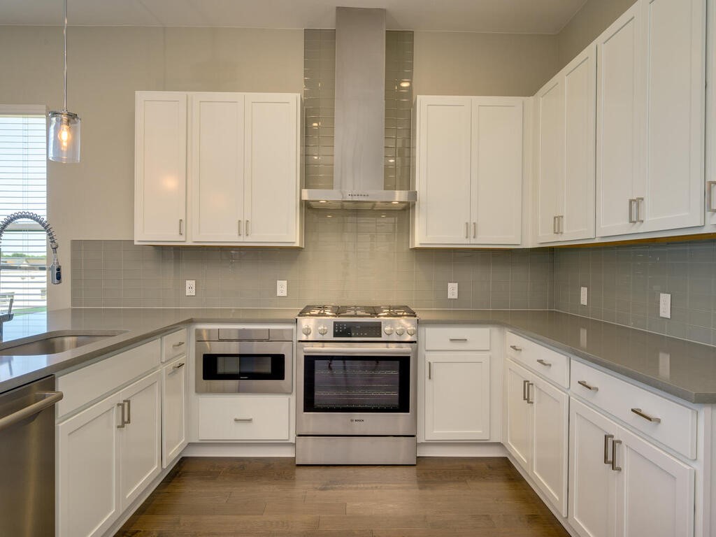 a kitchen with stainless steel appliances granite countertop white cabinets a sink and dishwasher