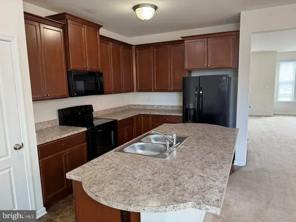 a kitchen with kitchen island a sink a refrigerator a stove and wooden cabinets