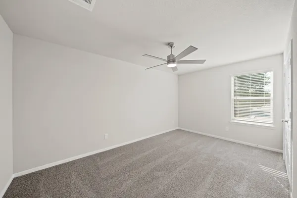 an empty room with a window and a fan