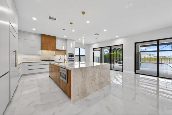a kitchen with kitchen island granite countertop a sink and white cabinets