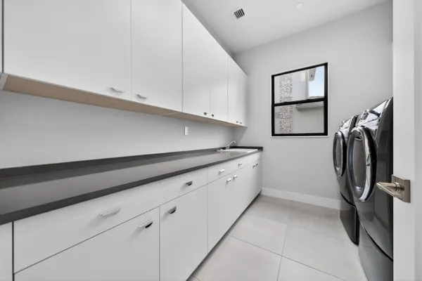 a large white kitchen with stainless steel appliances granite countertop a large window