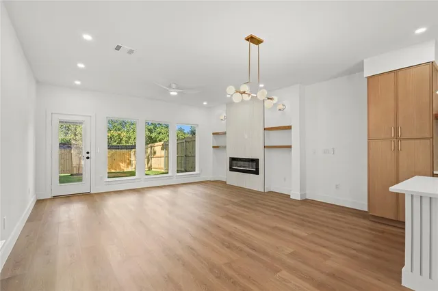 a view of an empty room with window and wooden floor