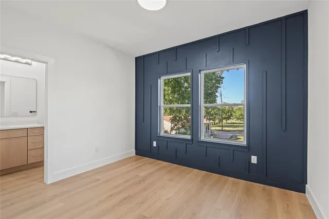 a view of an empty room with window and wooden floor