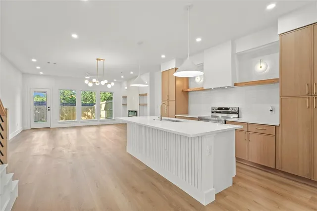 a large kitchen with stainless steel appliances a large counter top a stove a sink and a refrigerator