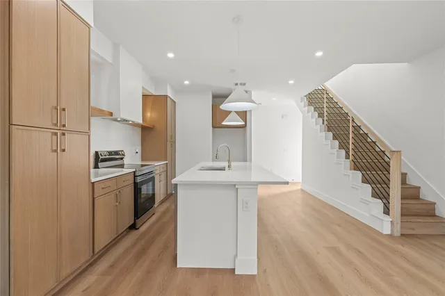 a kitchen with a sink a refrigerator and a stove top oven with wooden floor