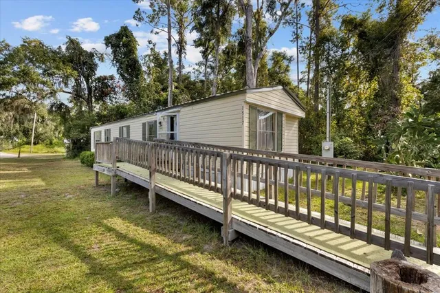 a view of a house with a wooden deck and a trees