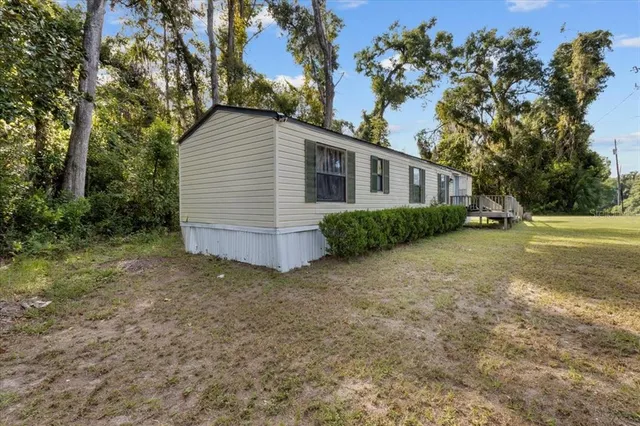 a view of a house with backyard and trees